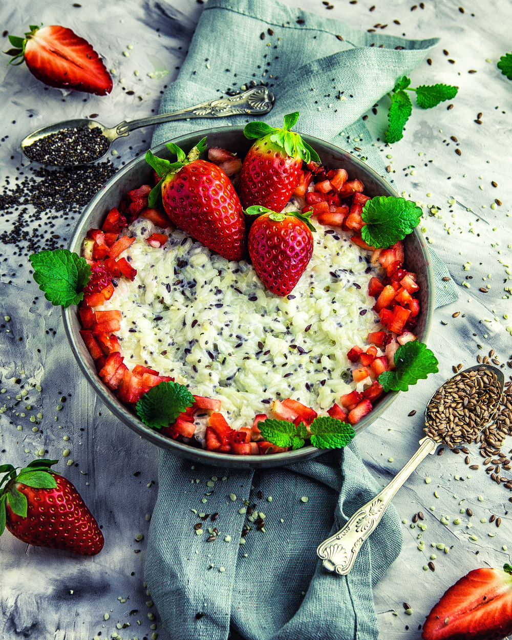 Schale mit cremigem Milchreis, getoppt mit Samen und frischen Erdbeeren