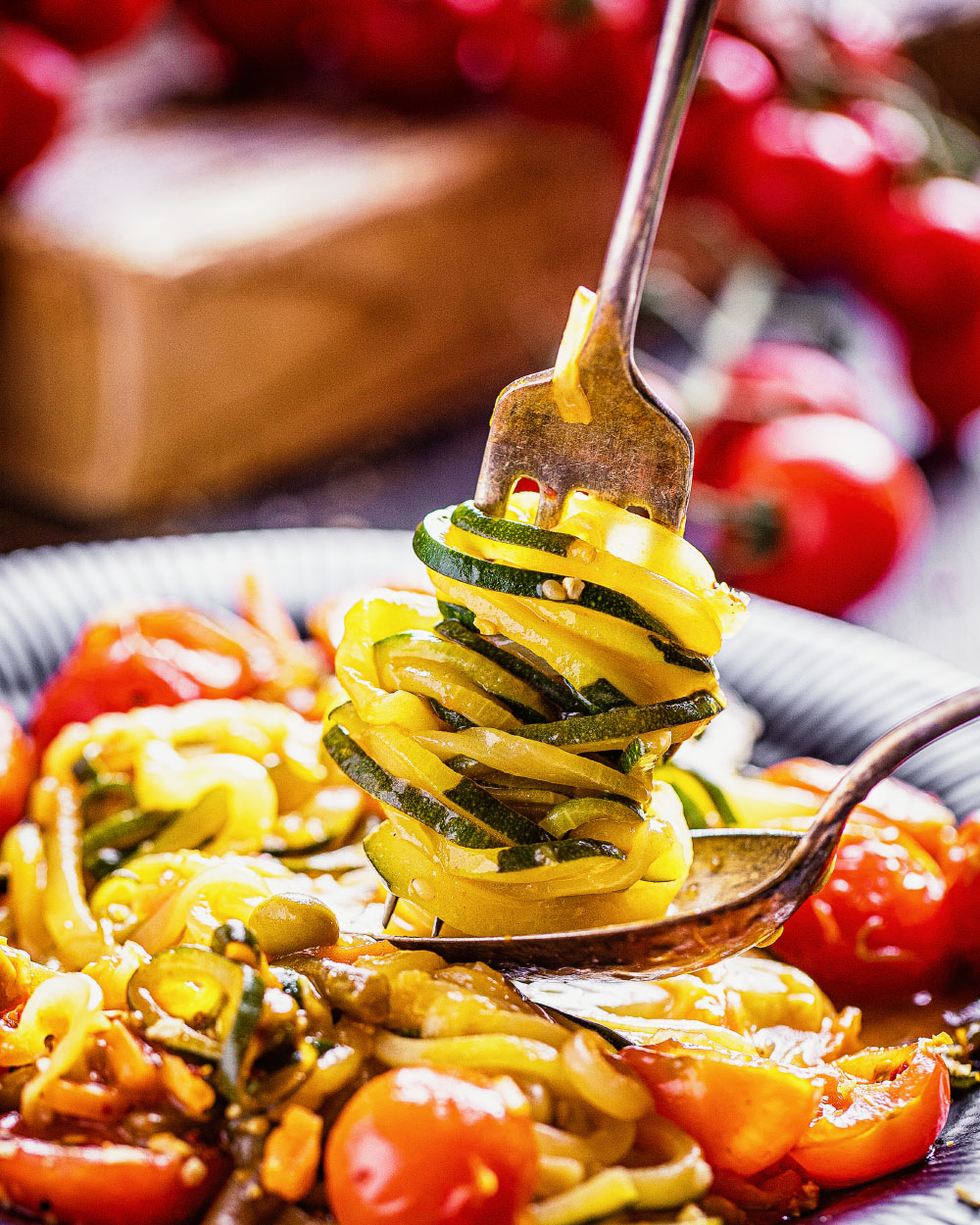 Zucchini-Nudeln mit Sauce und halbierten Cherry-Tomaten in einer Pfanne